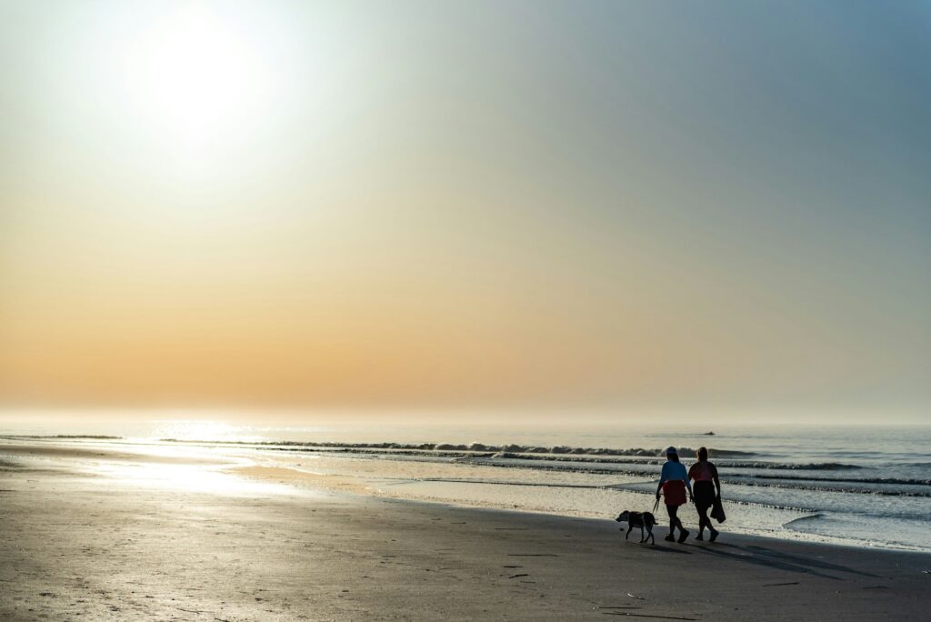 Girls with their dog strolling along the beach in Isle of Palms, SC, USA