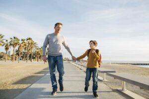 Father and son walking on beach promenade